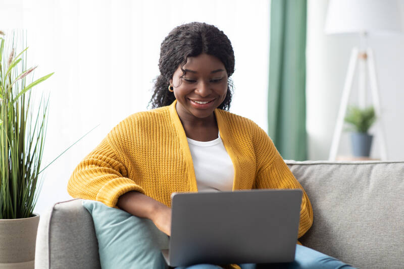 Smiling woman on laptop sitting on the sofa